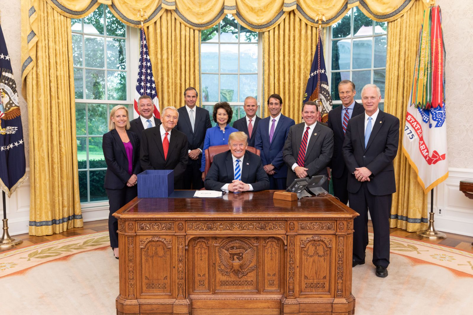 photo, President Donald J Trump poses in the Oval Office with staff including OPIC President and CEO Ray W Washburne after signing the BUILD Act