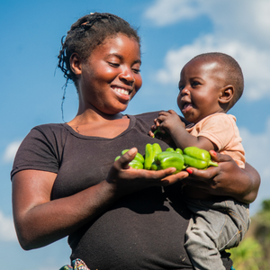 Zambian woman holding baby and green peppers