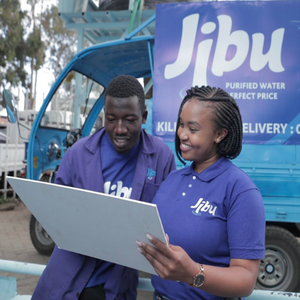 Two Jibu employees smiling in front of a van